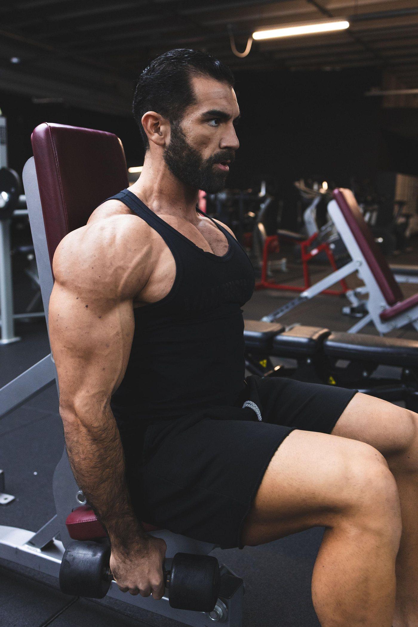 Abdullah Aziz in a black tank top, mid-set in the gym